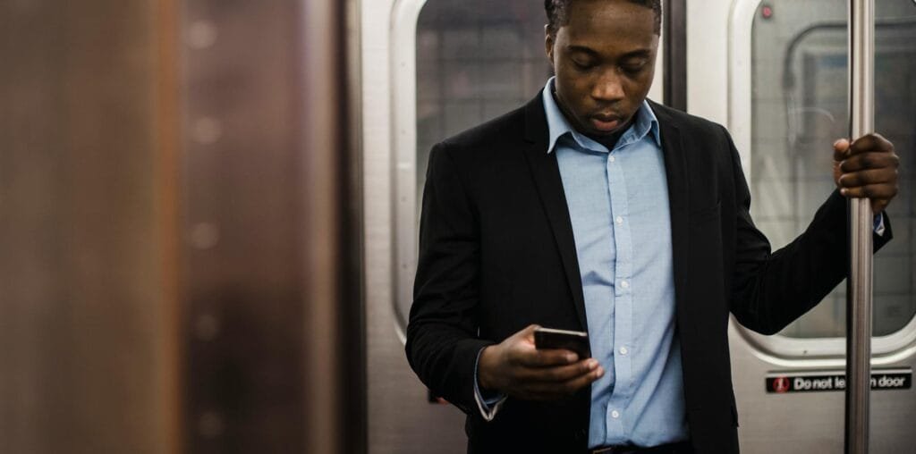 serious black office employee using smartphone on train