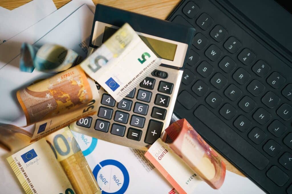 Billets en euros, calculatrice et ordinateur portable pour calculer le budget réel des études en Belgique