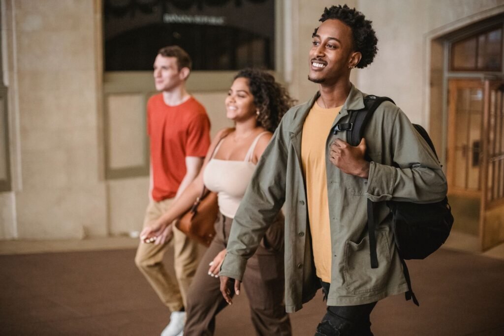 Étudiants d’origines diverses souriants marchant dans un couloir d’université
